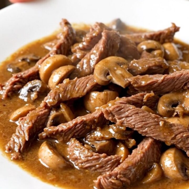 Vue de dessus d'un bœuf Stroganoff crémeux servi dans une assiette blanche, avec une sauce brillante.