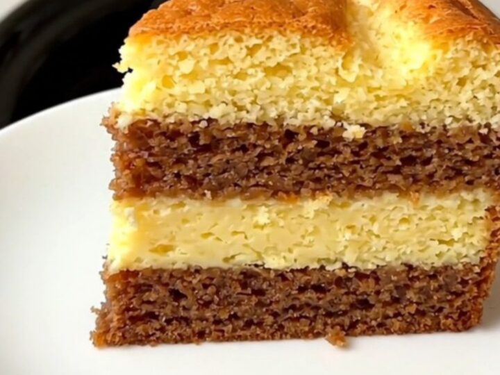 A close-up of a slice of vanilla magic cake showing three distinct layers on a white plate.