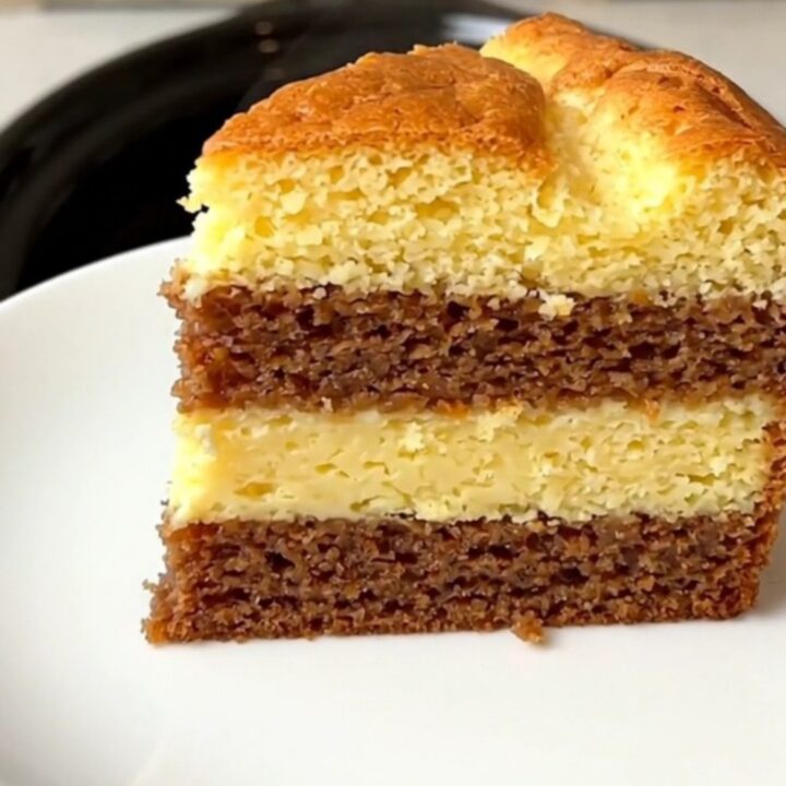 A close-up of a slice of vanilla magic cake showing three distinct layers on a white plate.