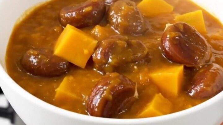 A steaming bowl of rich, glossy pumpkin and chestnut stew with visible rosemary sprigs and tender cubes of pumpkin.