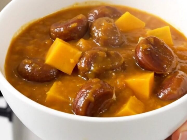 A steaming bowl of rich, glossy pumpkin and chestnut stew with visible rosemary sprigs and tender cubes of pumpkin.