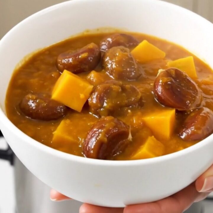 A steaming bowl of rich, glossy pumpkin and chestnut stew with visible rosemary sprigs and tender cubes of pumpkin.