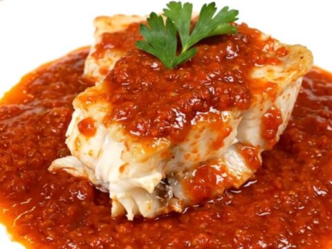 A bowl of monkfish armoricaine in a rich tomato sauce with carrots.