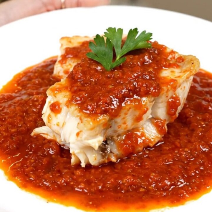 A bowl of monkfish armoricaine in a rich tomato sauce with carrots.