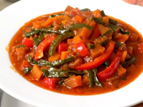 Vue de dessus d'une mijoteuse remplie de piperade basque avec des poivrons fondants.