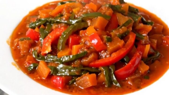 Vue de dessus d'une mijoteuse remplie de piperade basque avec des poivrons fondants.