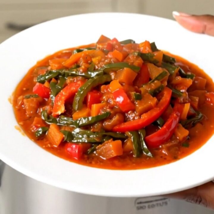 Vue de dessus d'une mijoteuse remplie de piperade basque avec des poivrons fondants.