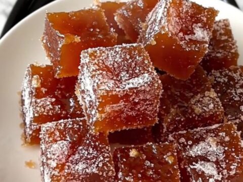 A rustic platter featuring squares of ruby-amber quince paste arranged next to slices of aged Manchego cheese.