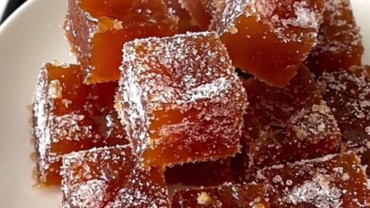 A rustic platter featuring squares of ruby-amber quince paste arranged next to slices of aged Manchego cheese.