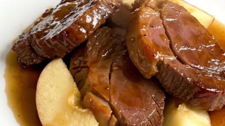 A top-down view of raw veal tendrons, apple wedges, and sliced onions in a slow cooker, ready to be cooked.