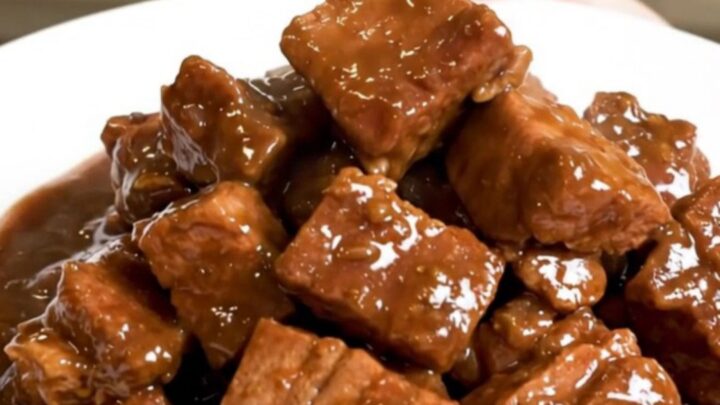 A close-up of a finished Slow Cooker Pork Carbonnade served in a bowl, featuring tender pork cubes and a rich