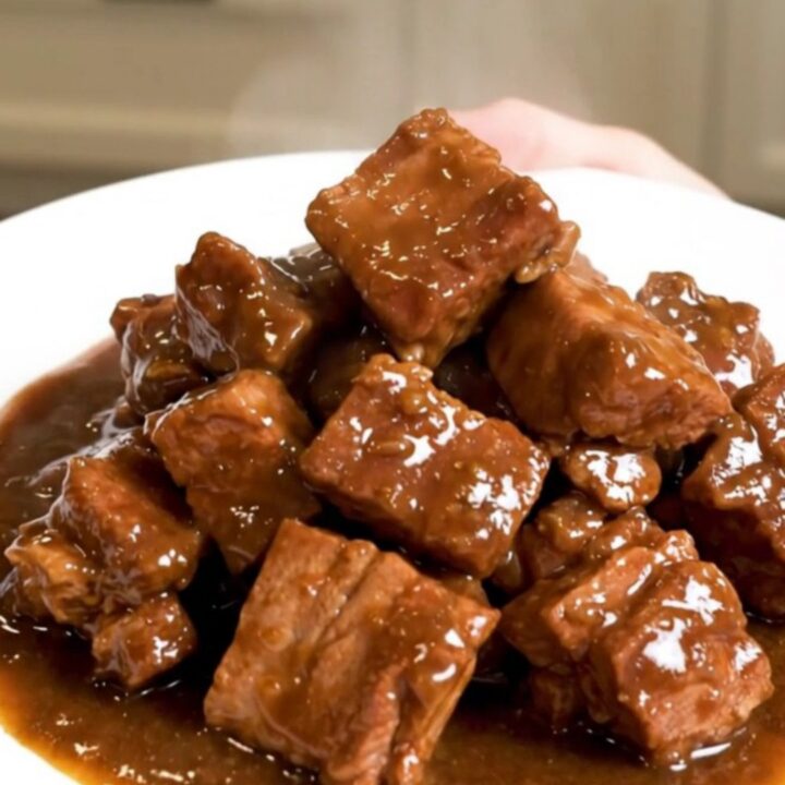 A close-up of a finished Slow Cooker Pork Carbonnade served in a bowl, featuring tender pork cubes and a rich