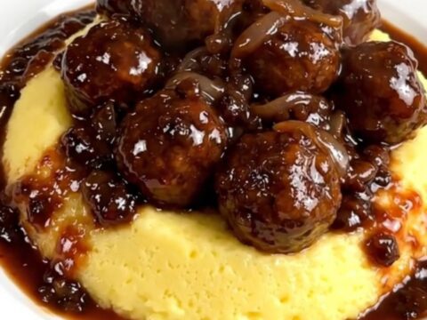 A plate of tender smoked sausages served over creamy polenta with a rich red wine and onion sauce.