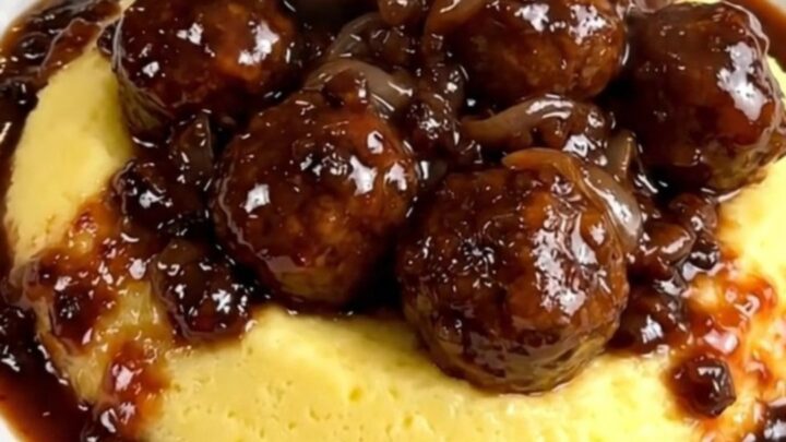 A plate of tender smoked sausages served over creamy polenta with a rich red wine and onion sauce.