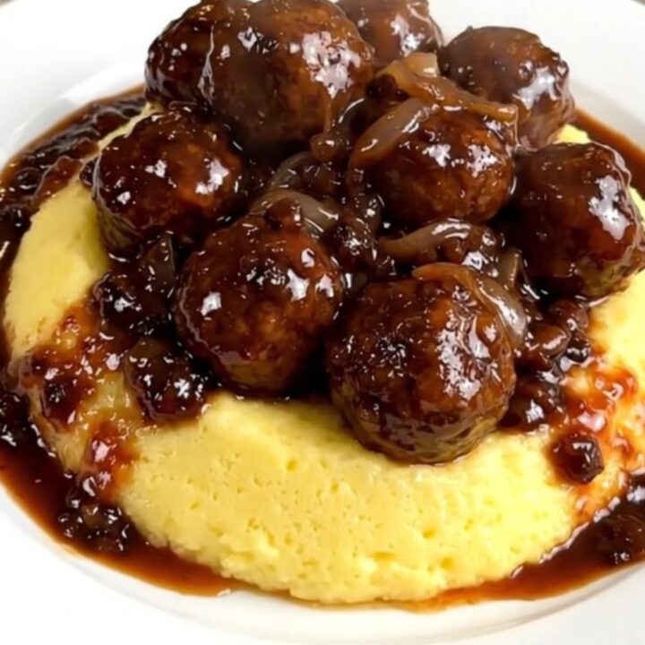 A plate of tender smoked sausages served over creamy polenta with a rich red wine and onion sauce.