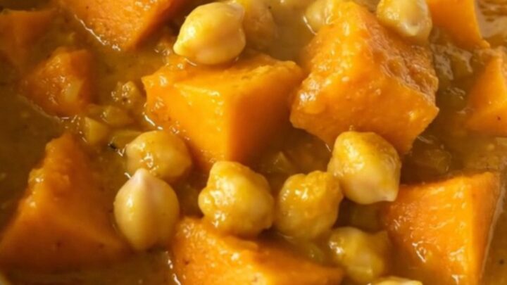 A steaming, golden bowl of butternut squash and chickpea curry topped with fresh herbs.