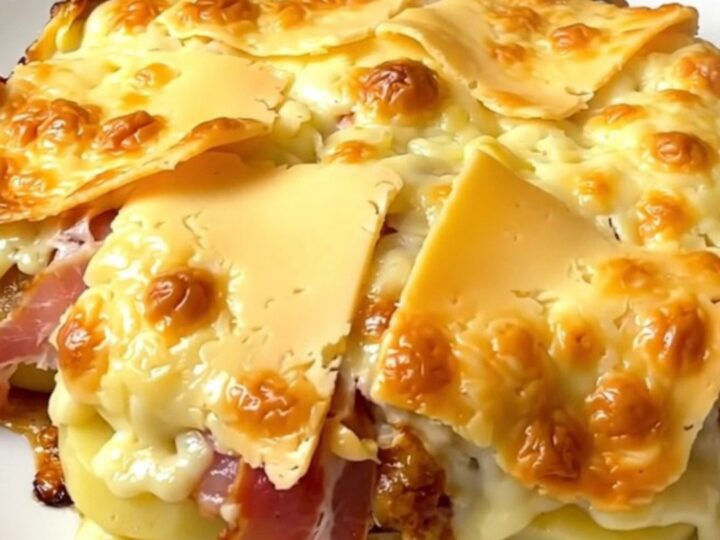 A top-down view of a black slow cooker filled with layers of potatoes, bacon, and thick slices of Maroilles cheese.