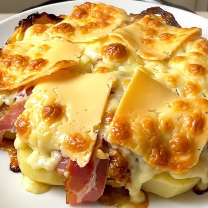 A top-down view of a black slow cooker filled with layers of potatoes, bacon, and thick slices of Maroilles cheese.