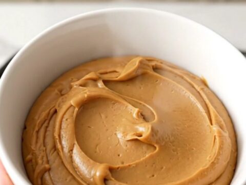 A ceramic bowl filled with glossy, smooth speculoos cookie butter spread.