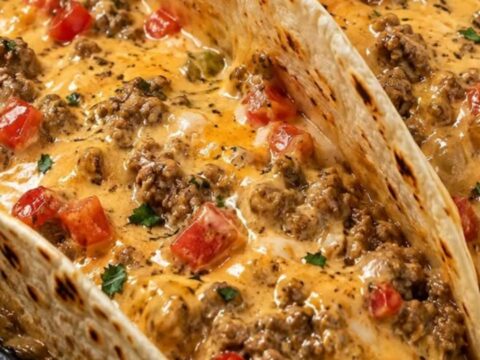 A cast iron skillet filled with cheesy Rotel beef, served with soft flour tortillas on a wooden table.
