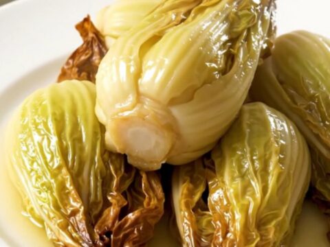 A plate of golden, tender braised endives with a light buttery glaze.