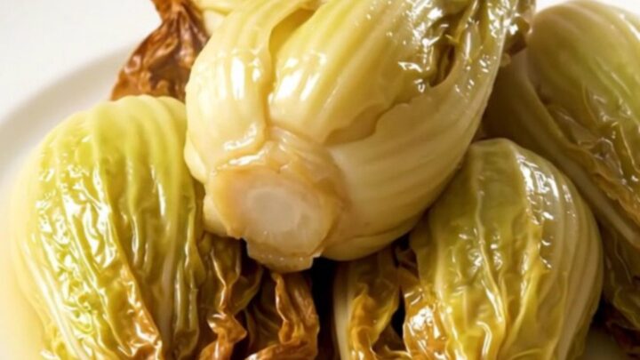 A plate of golden, tender braised endives with a light buttery glaze.