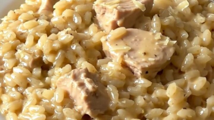 A top-down view of creamy chicken and parmesan risotto in a slow cooker on a white countertop.