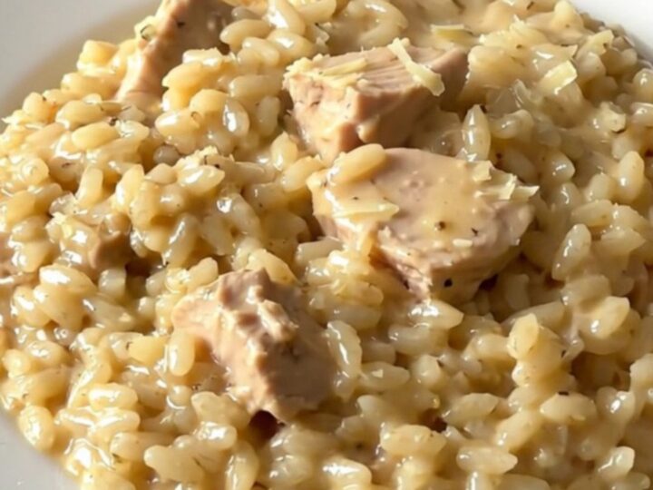 A top-down view of creamy chicken and parmesan risotto in a slow cooker on a white countertop.