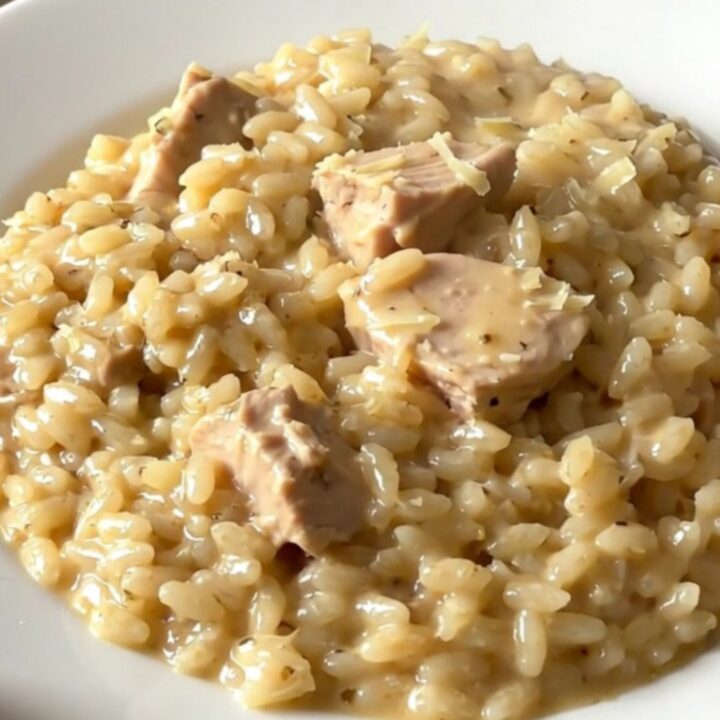 A top-down view of creamy chicken and parmesan risotto in a slow cooker on a white countertop.
