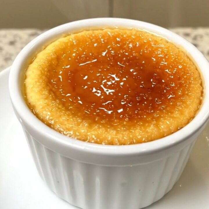 A top-down view of four ramekins of creamy vanilla crème brûlée arranged in a slow cooker.