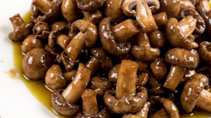 A close-up shot of a slow cooker filled with fresh wild mushrooms, diced shallots, and garlic.