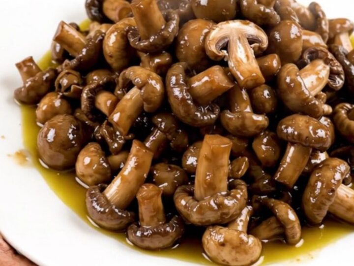 A close-up shot of a slow cooker filled with fresh wild mushrooms, diced shallots, and garlic.
