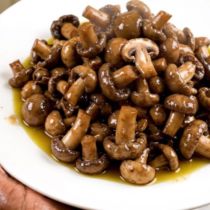 A close-up shot of a slow cooker filled with fresh wild mushrooms, diced shallots, and garlic.
