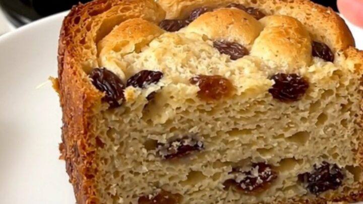 A slow cooker filled with freshly made bread pudding topped with raisins.