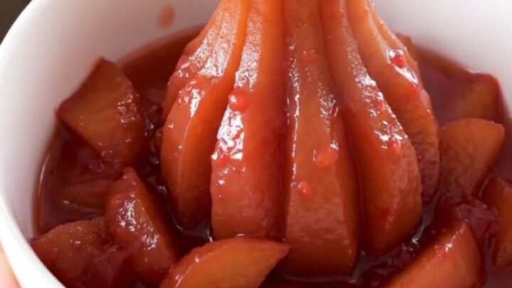 A white bowl filled with glossy, rosy quince and apple compote, steaming gently in a bright kitchen.