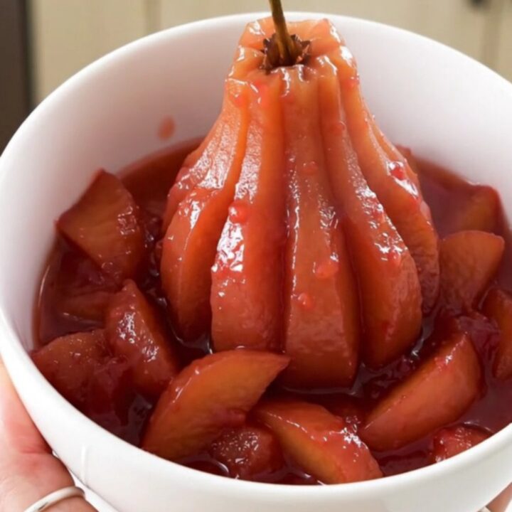 A white bowl filled with glossy, rosy quince and apple compote, steaming gently in a bright kitchen.