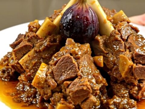 A close-up of a tender lamb tagine with figs and honey served on a white plate.