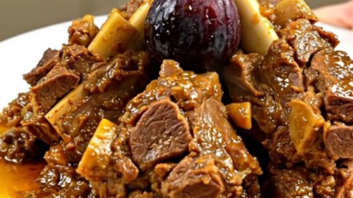 A close-up of a tender lamb tagine with figs and honey served on a white plate.