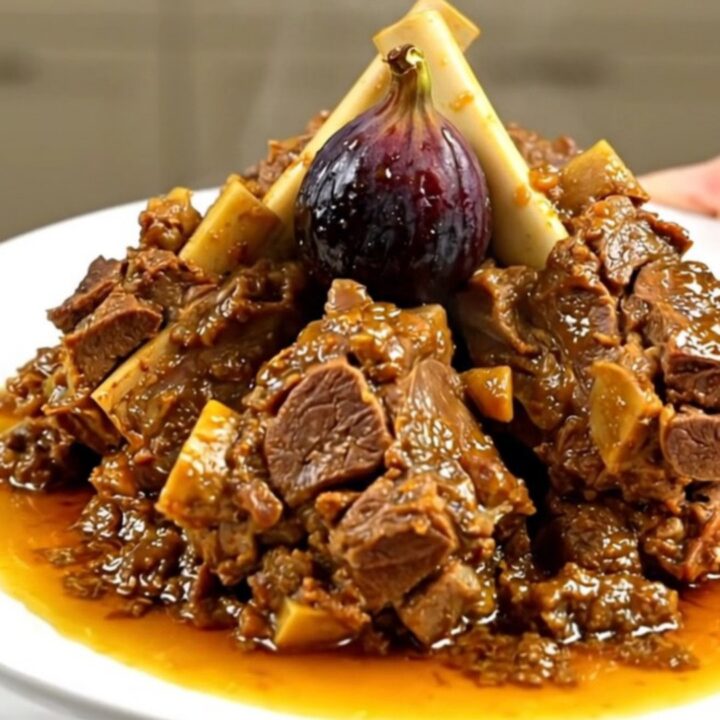 A close-up of a tender lamb tagine with figs and honey served on a white plate.