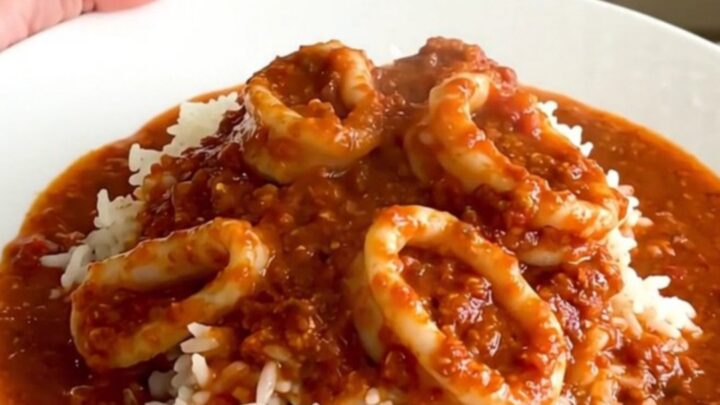 Slow cooker filled with tender calamari rings simmering in a rich, red tomato and wine sauce.