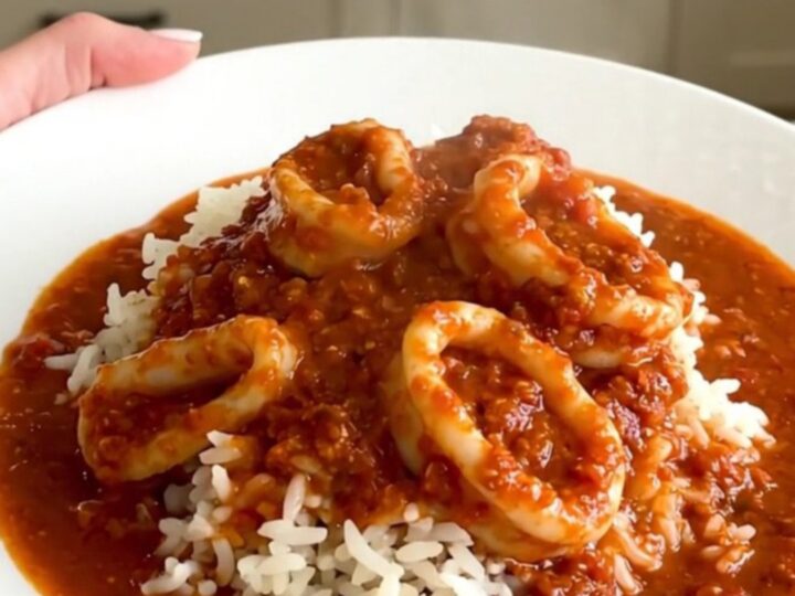 Slow cooker filled with tender calamari rings simmering in a rich, red tomato and wine sauce.