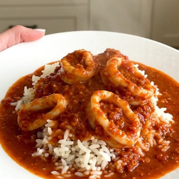 Slow cooker filled with tender calamari rings simmering in a rich, red tomato and wine sauce.