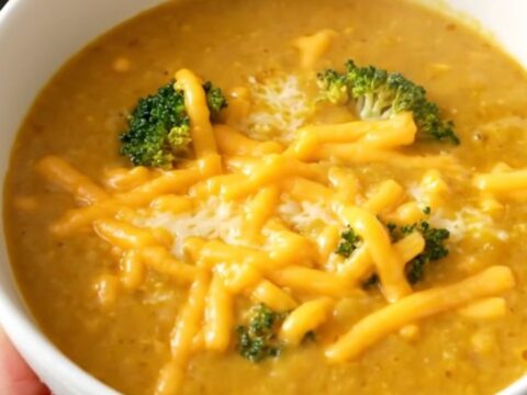 A white bowl filled with creamy broccoli cheddar potato soup, topped with melted cheddar cheese.