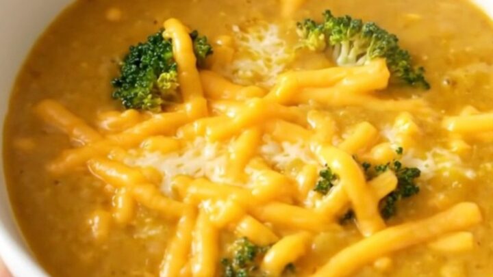 A white bowl filled with creamy broccoli cheddar potato soup, topped with melted cheddar cheese.