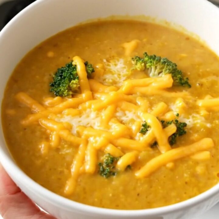 A white bowl filled with creamy broccoli cheddar potato soup, topped with melted cheddar cheese.