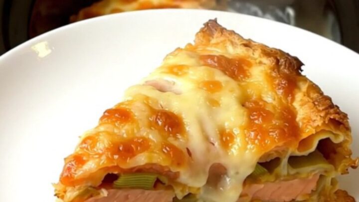 A top-down view of a slow cooker filled with layers of salmon, leeks, and creamy béchamel lasagna.