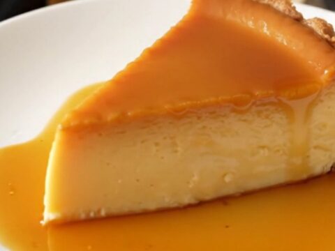 A thick, glossy slice of golden crustless custard tart on a white plate.