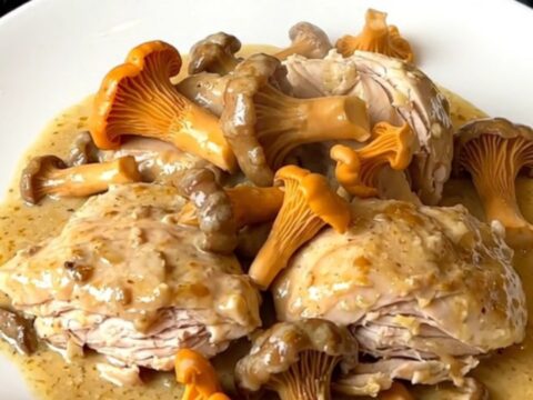 Creamy slow cooker chicken with golden chanterelles and shallots served on a white plate.