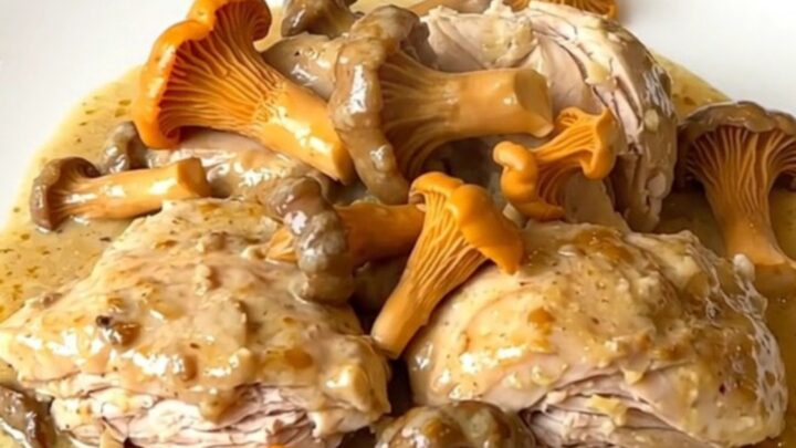 Creamy slow cooker chicken with golden chanterelles and shallots served on a white plate.