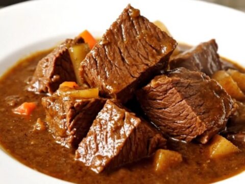 Bœuf bourguignon mijoté dans une mijoteuse noire sur un plan de travail en quartz blanc.